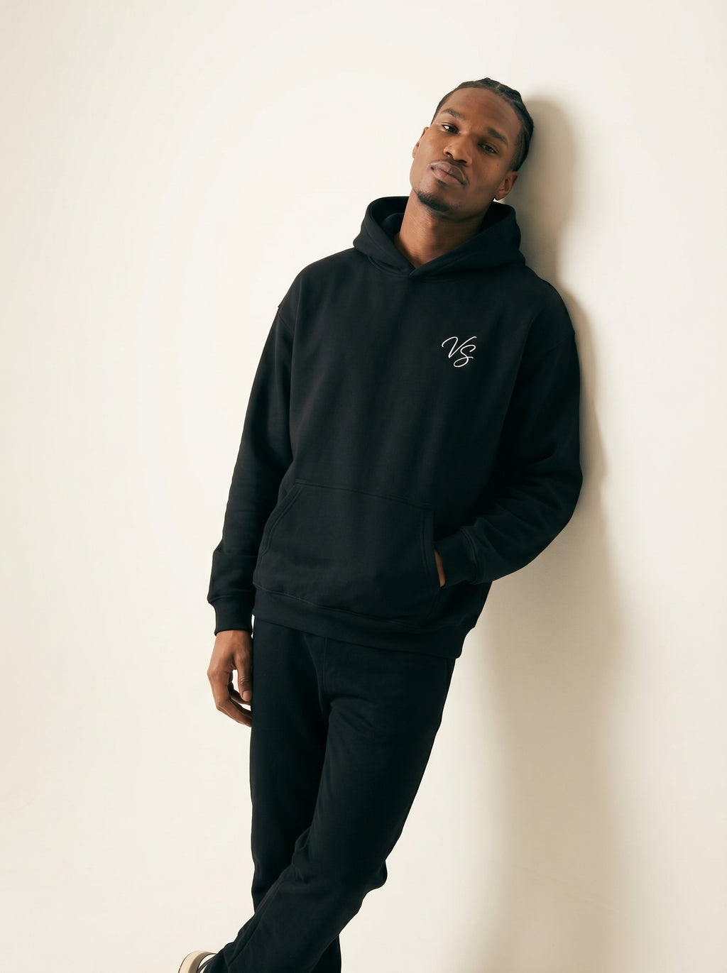 Person wearing a black hoodie with a logo against a white background