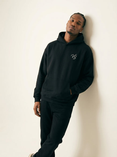 Person wearing a black hoodie with a logo against a white background