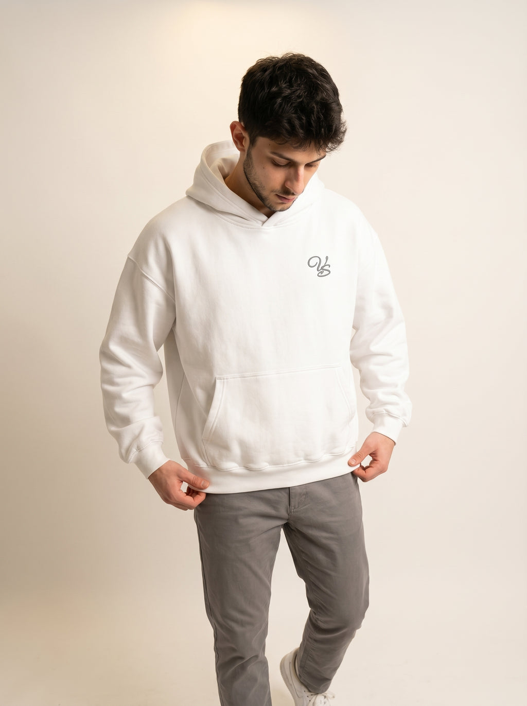 Man wearing a white hoodie with a logo on a beige background