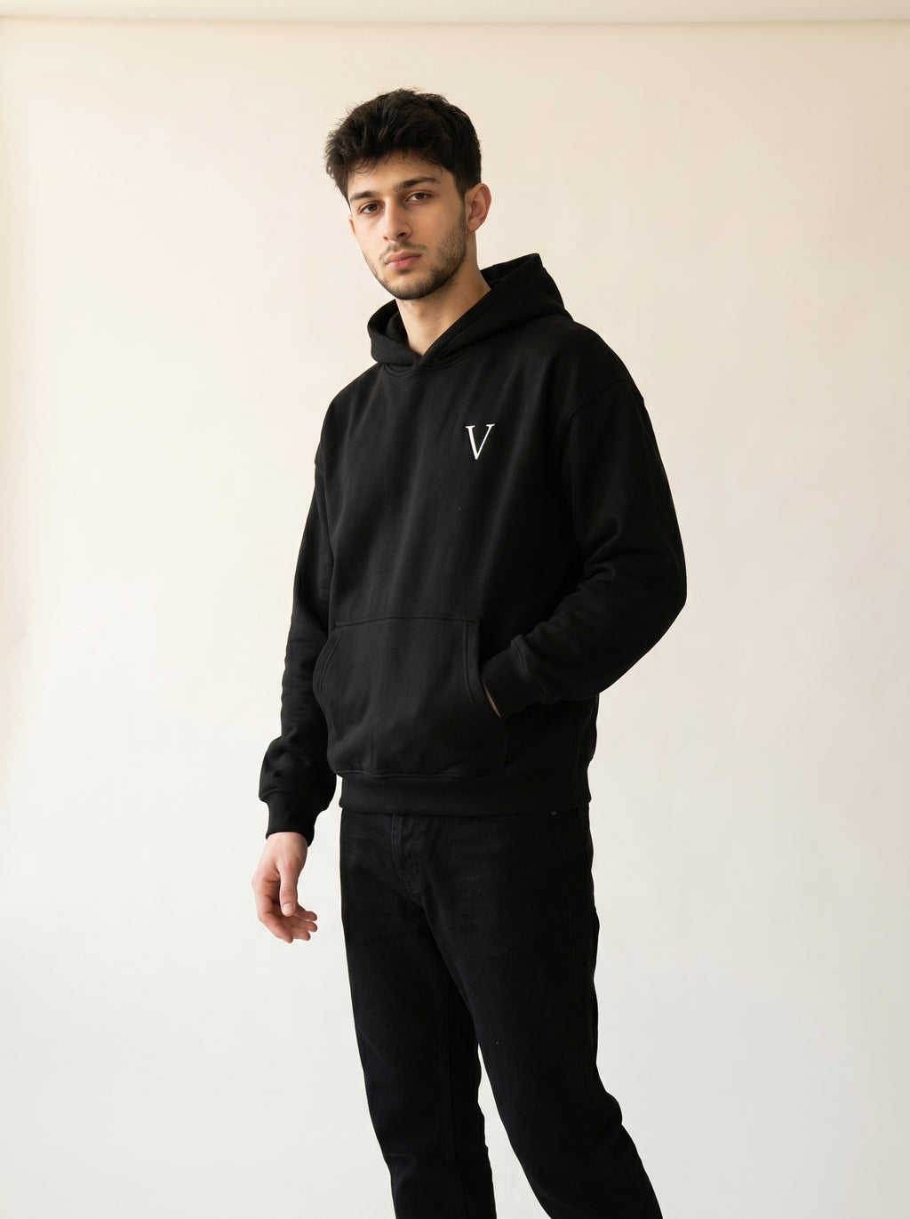Man wearing a black hoodie with a logo on a plain background