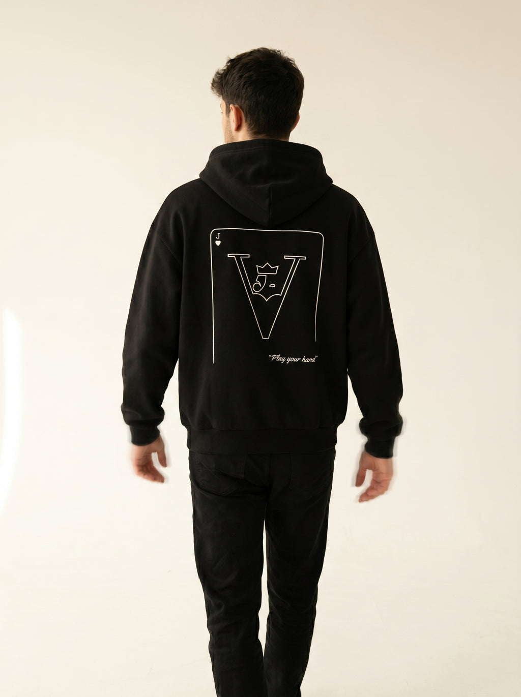 Person wearing a black hoodie with a logo on the back against a plain background