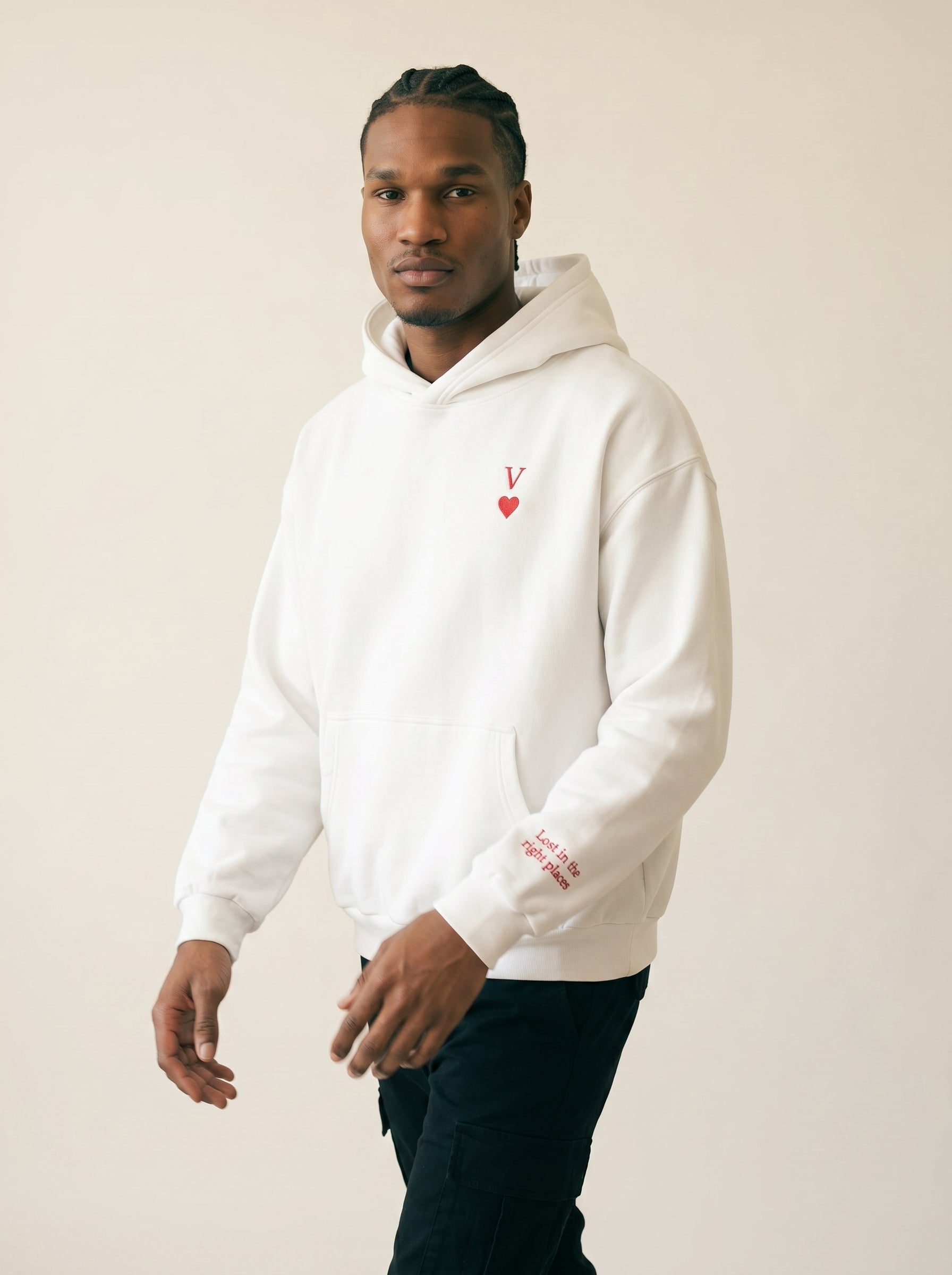 Man wearing a white hoodie with a logo on a beige background