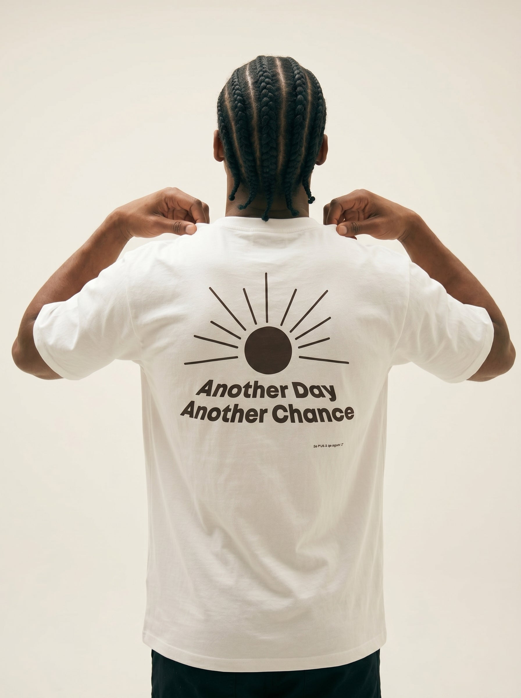 Person wearing a white t-shirt with a sun design and text on the back, against a plain background