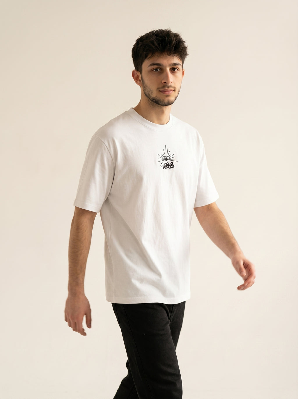 Man wearing a white t-shirt with a small graphic on a beige background