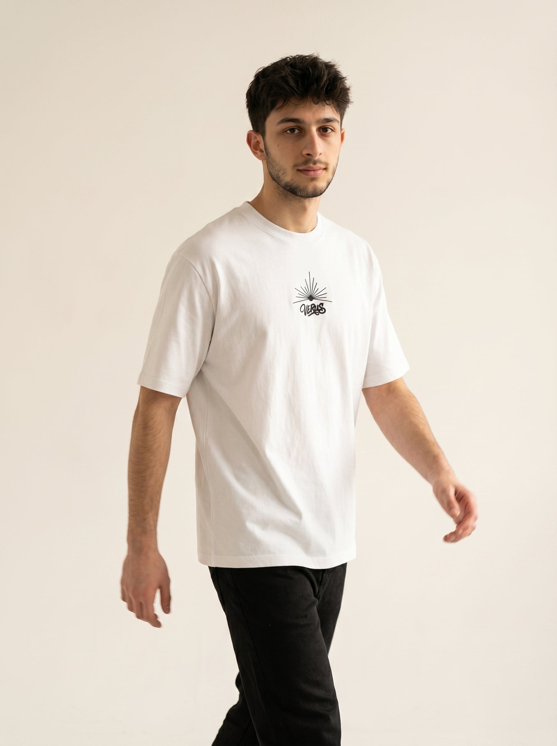 Man wearing a white t-shirt with a small graphic on a beige background