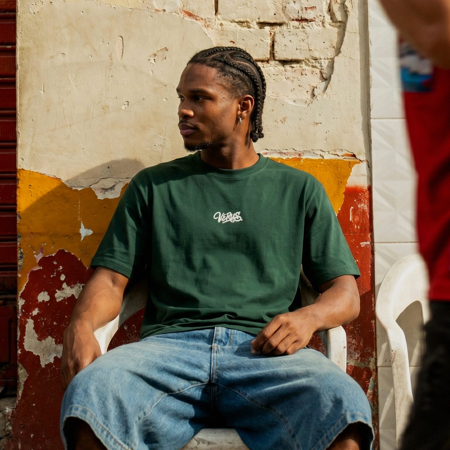 Person sitting on a chair against a textured wall with peeling paint.