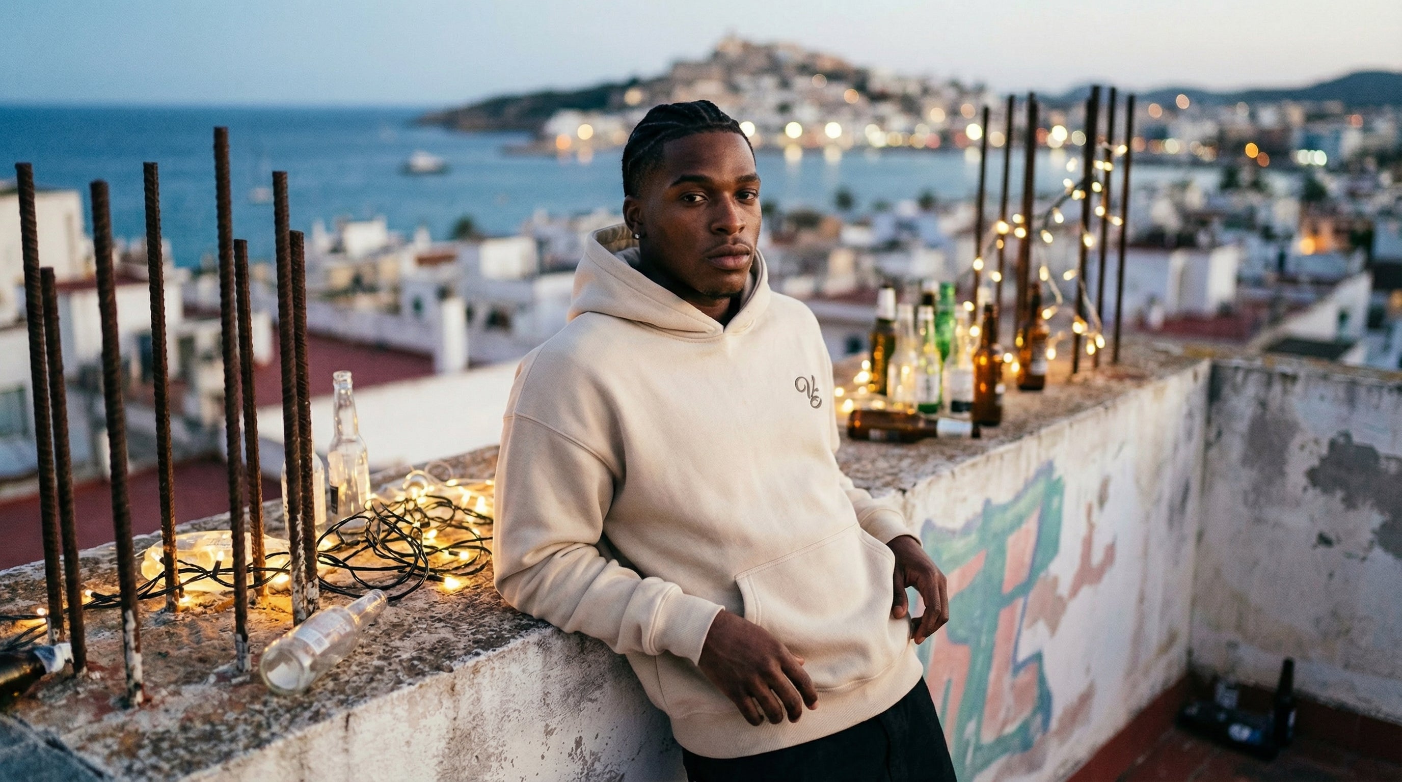 Person wearing a beige hoodie on a rooftop with ocean view