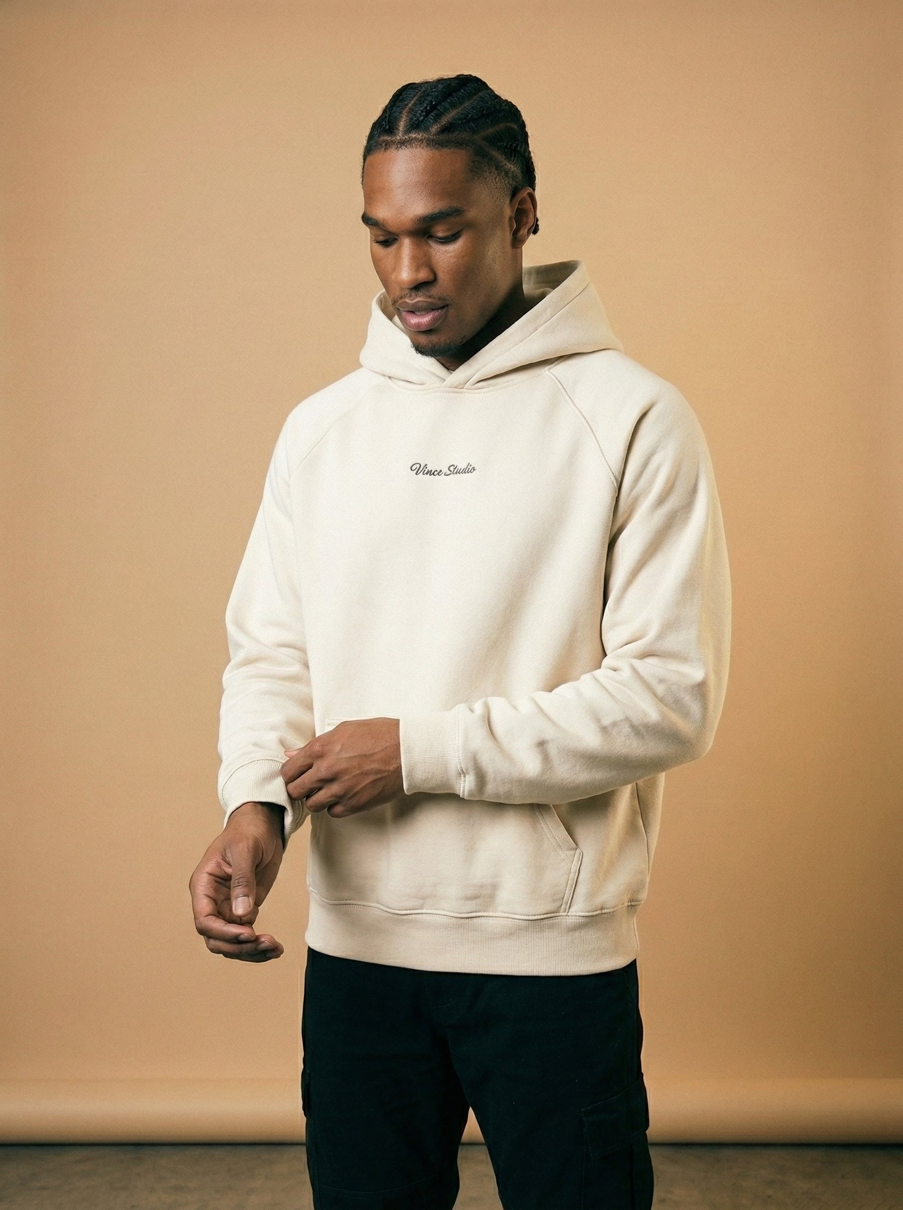 Man wearing a beige hoodie with a logo on a beige background