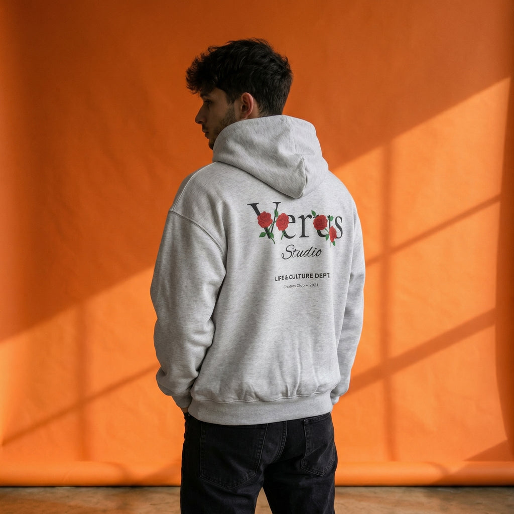 Person wearing a gray hoodie with 'Vermis Studio' branding against an orange wall.