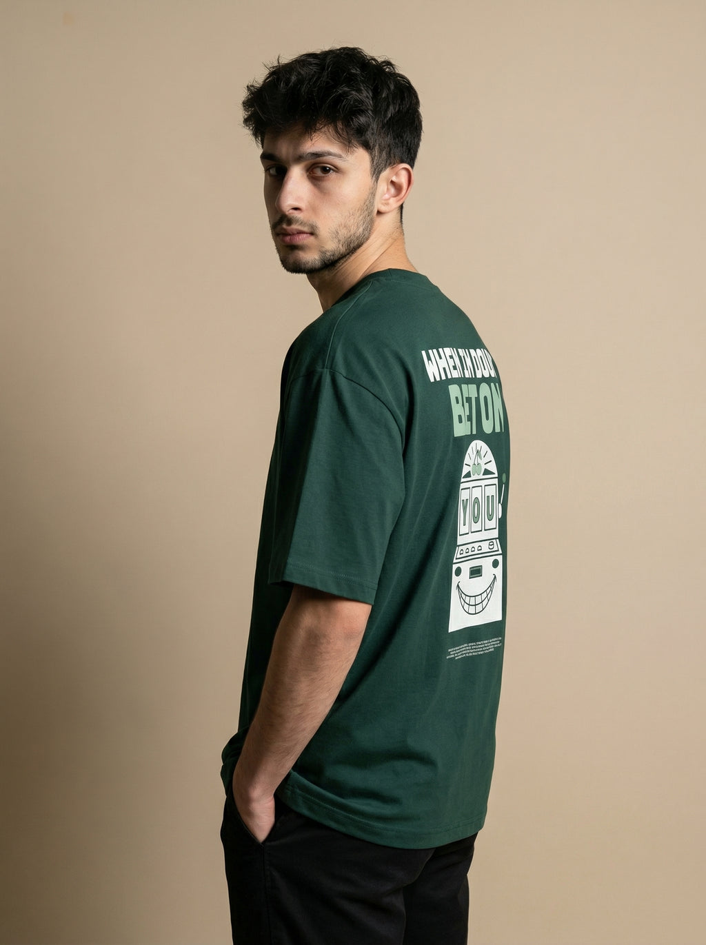 Man wearing a green t-shirt with a graphic design on the back against a beige background