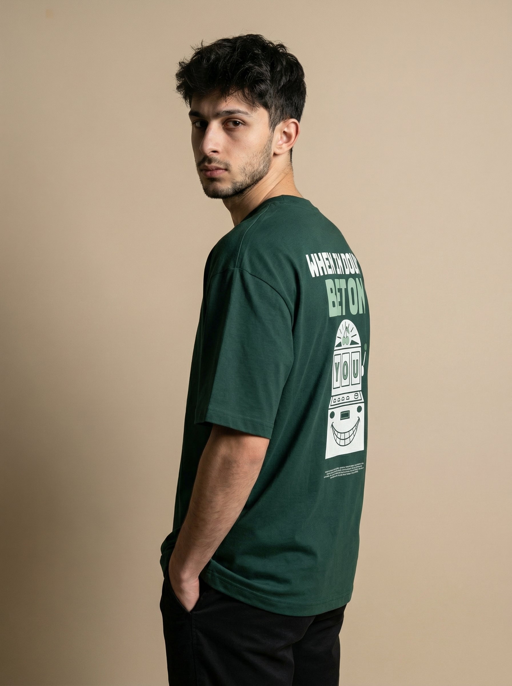 Man wearing a green t-shirt with a graphic design on the back against a beige background