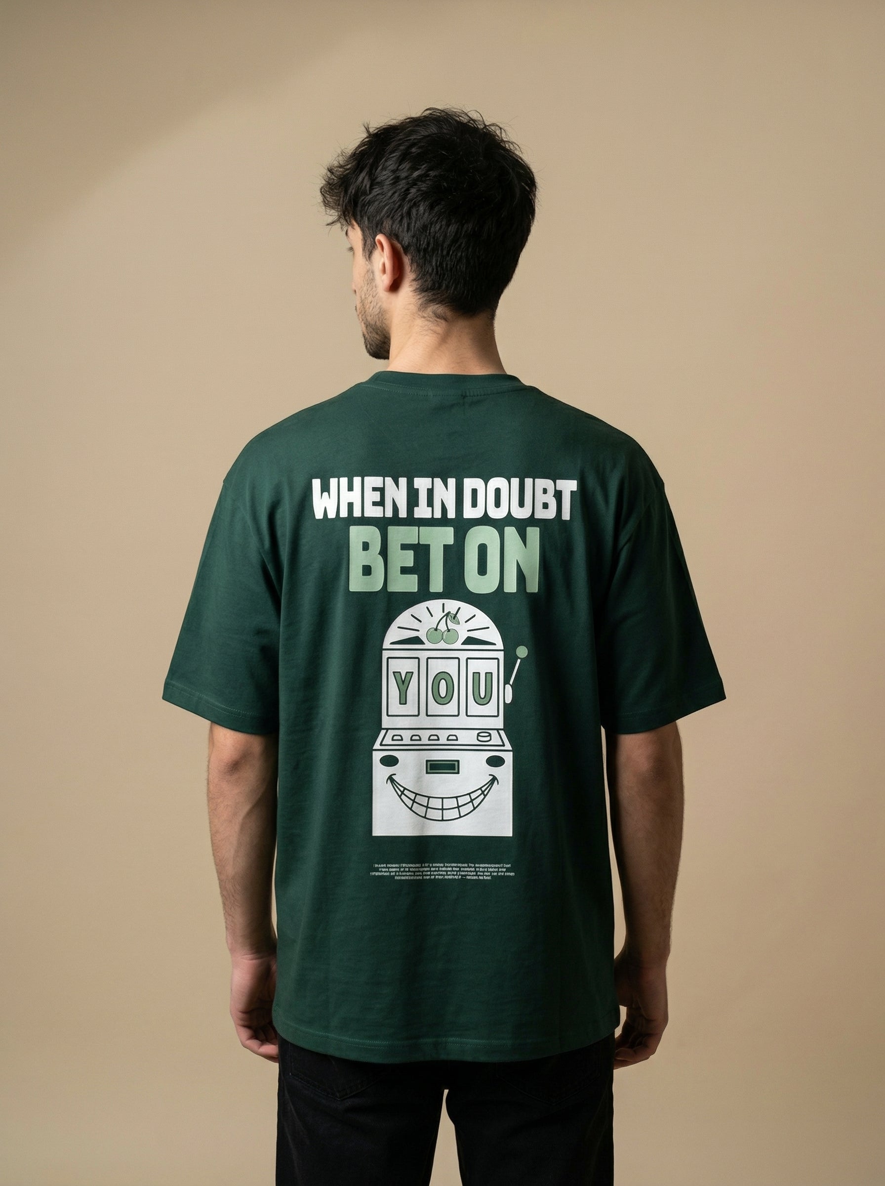 Person wearing a green t-shirt with text and graphic on the back against a beige background