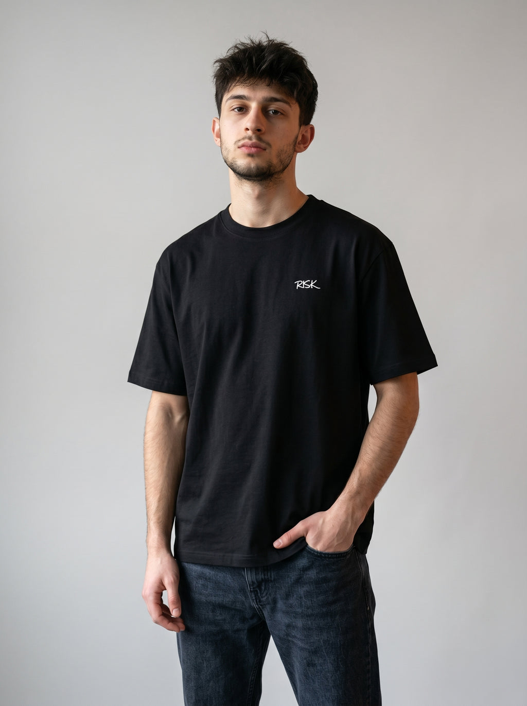 Man wearing a black t-shirt with a logo on a plain background