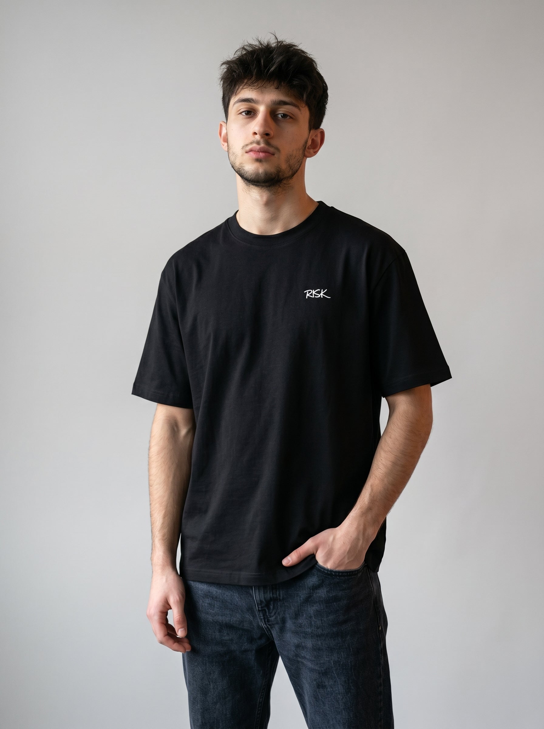 Man wearing a black t-shirt with a logo on a plain background