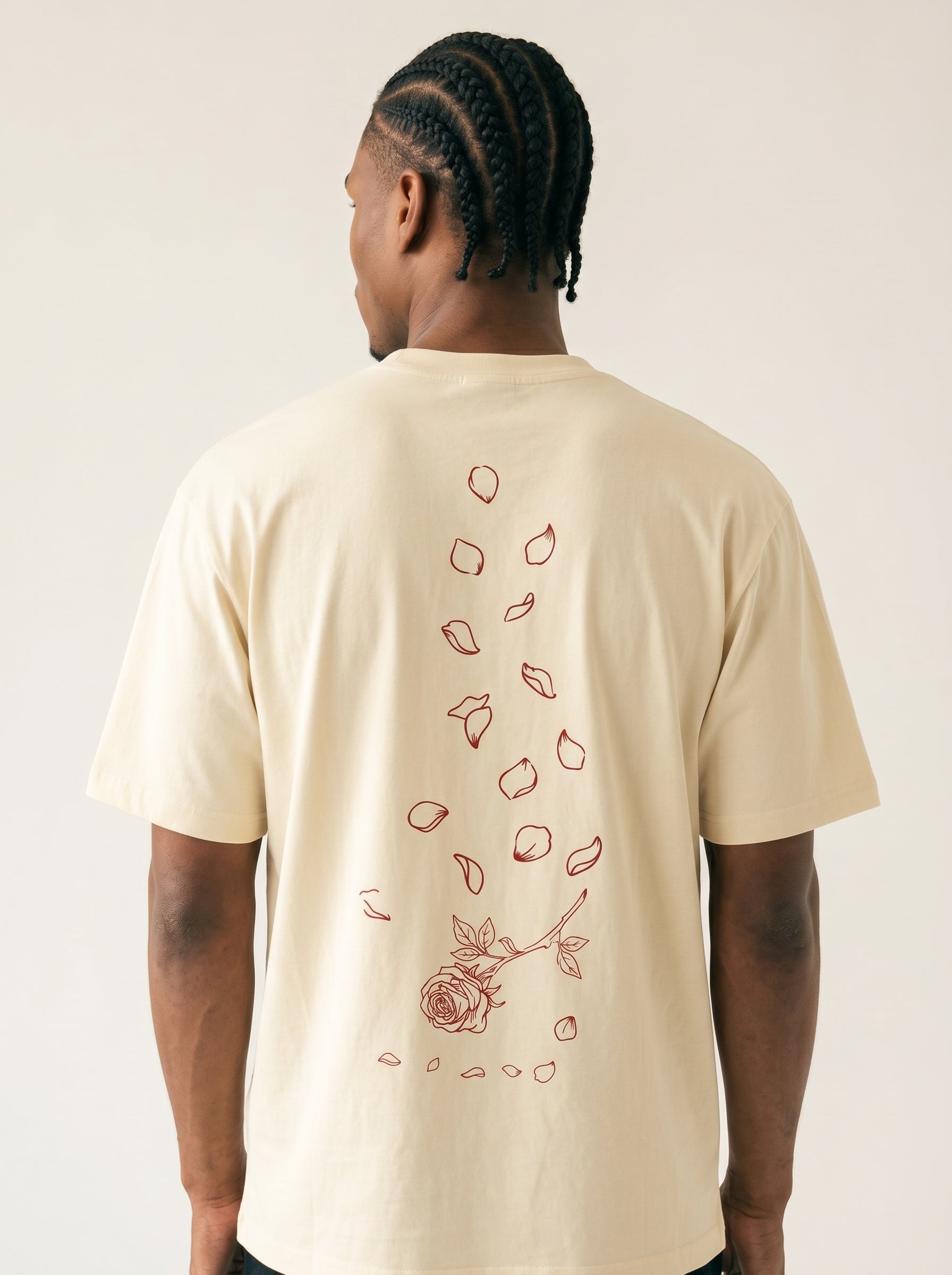 Person wearing a beige t-shirt with a rose design on the back against a plain background