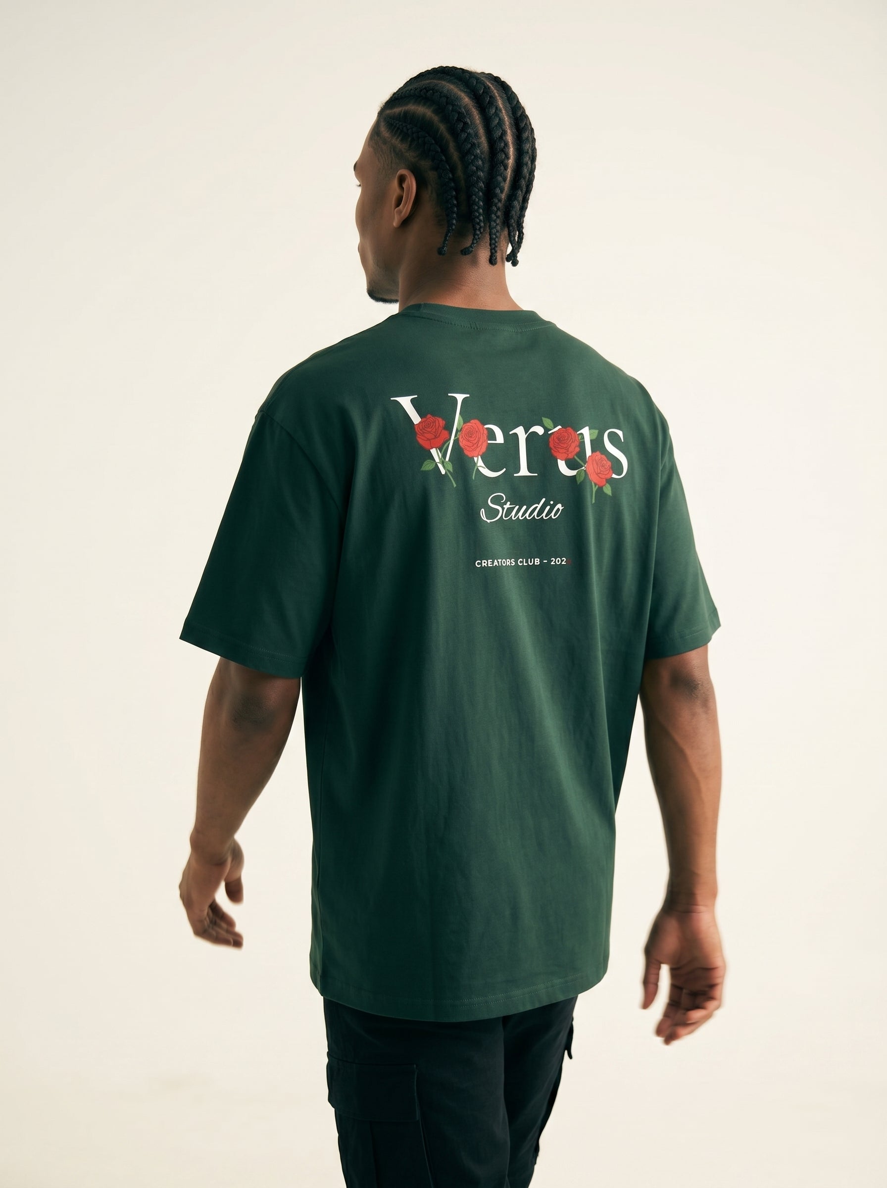 Person wearing a green t-shirt with 'Verus Studio' logo on the back against a beige background