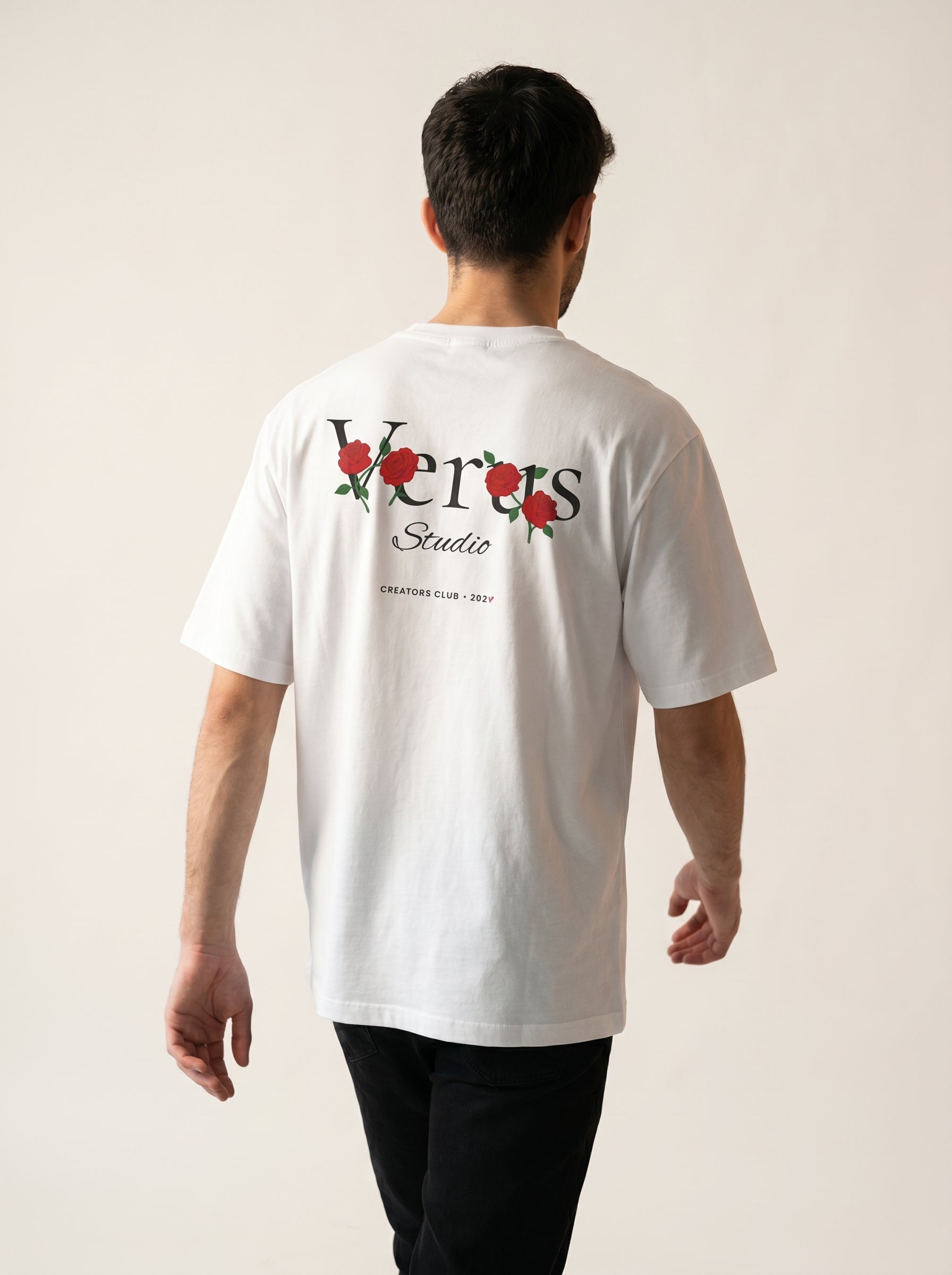 Person wearing a white t-shirt with a logo on the back against a plain background