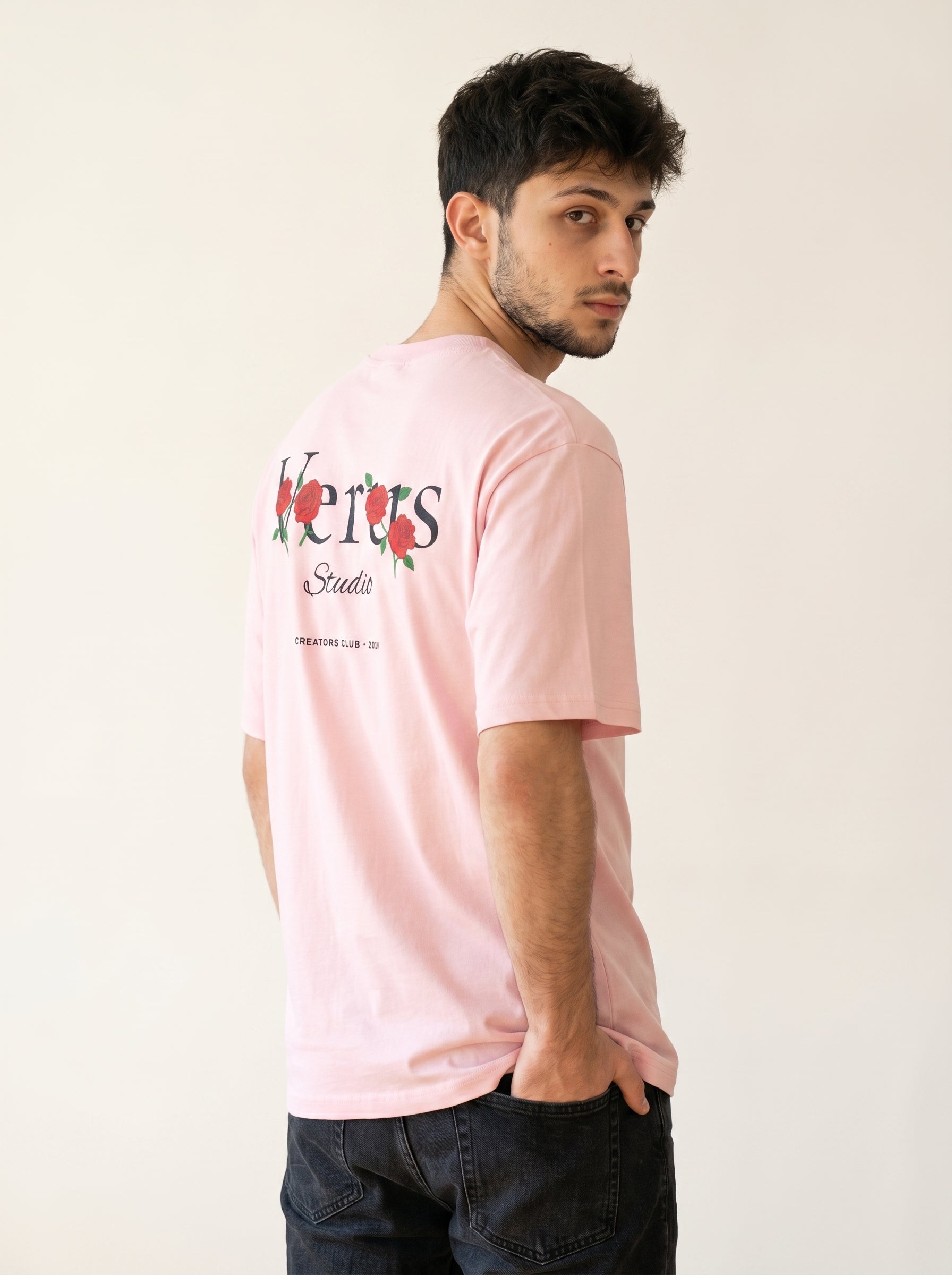 Man wearing a pink t-shirt with a logo on a plain background